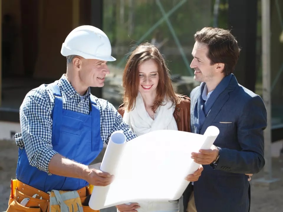 A couple and construction worker looking at a building plan
