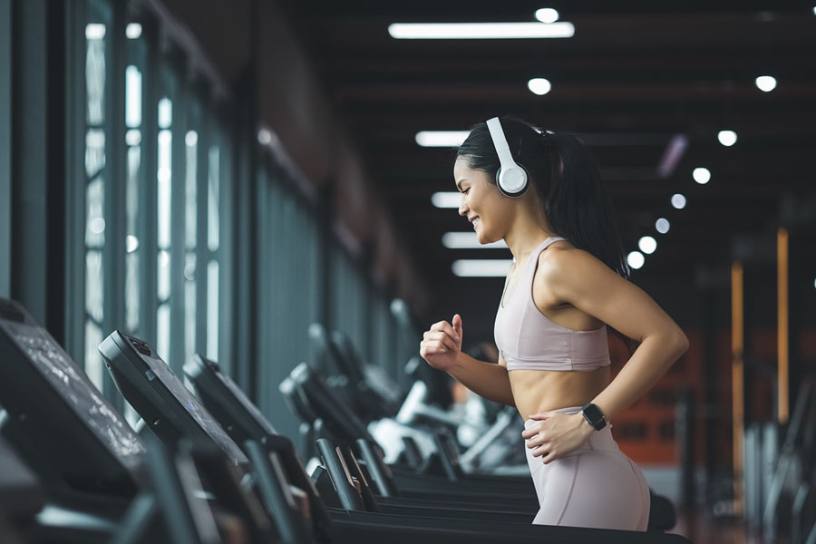 Young woman runs on treadmill in modern gym