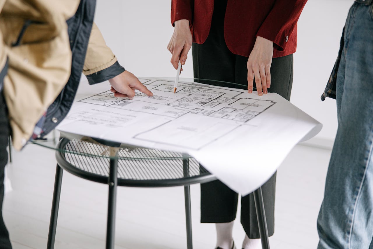 Three people review floorplans on a small table
